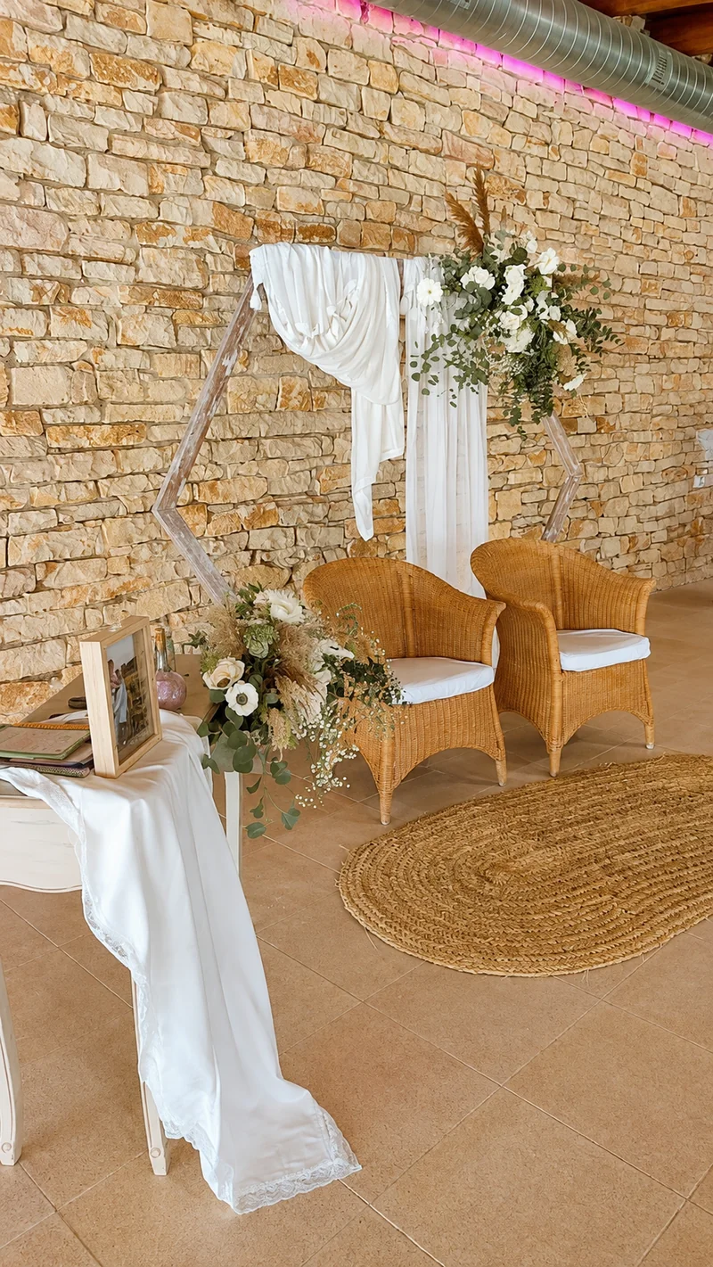 Salón de piedra montado para ceremonia bajo techo, con sillas orientadas al altar
