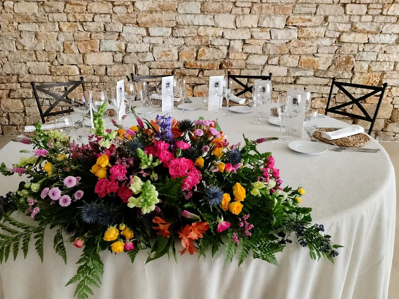 Un centro de flores de color sobre el mantel blanco.